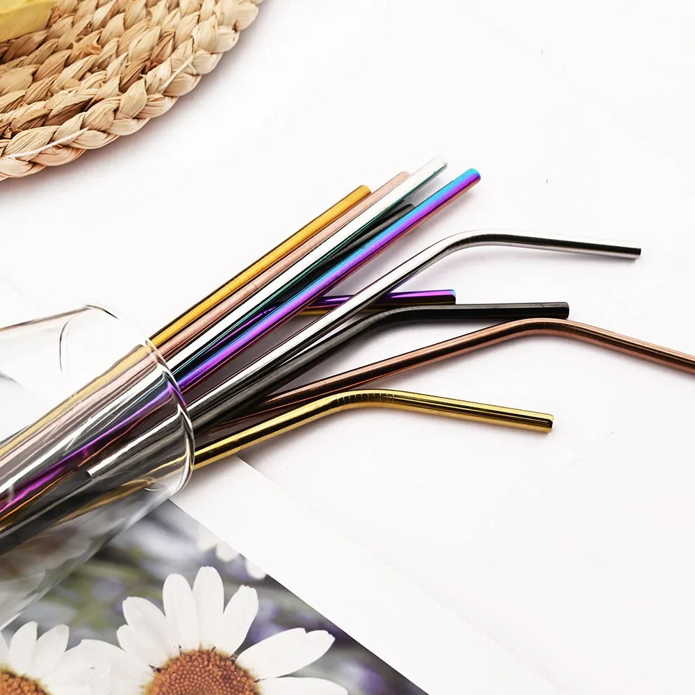 A set of reusable metal drinking straws in various colors and finishes laid on a white surface.