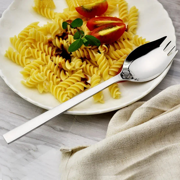 Edelstahl-Gabel- und Löffelservice auf weißem Teller mit Pasta und Tomatengarnitur