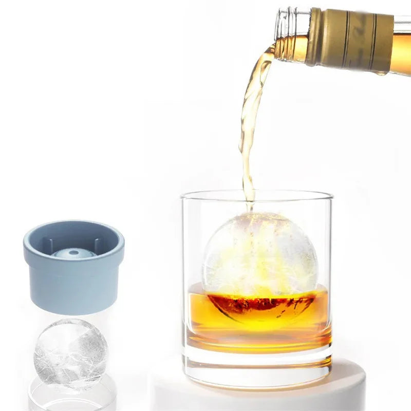 A glass of amber liquid being filled with a golden-colored liquid from a bottle, next to a stackable ice mold.