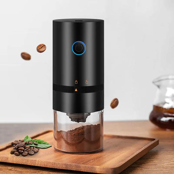 A black portable USB-C burr coffee grinder sitting on a wooden board with coffee beans and ground coffee visible.