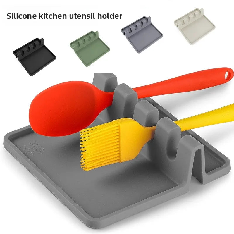 A silicone kitchen utensil holder featuring various silicone trays and a large orange spoon and yellow brush resting in the m