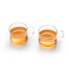 A set of two clear glass tea cups filled with amber-colored tea.