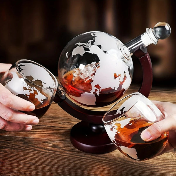 Eine Hand hält ein Glas bernsteinfarbenes Getränk neben ein elegantes Dekantier-Set mit Holzständer und Whiskygläsern.