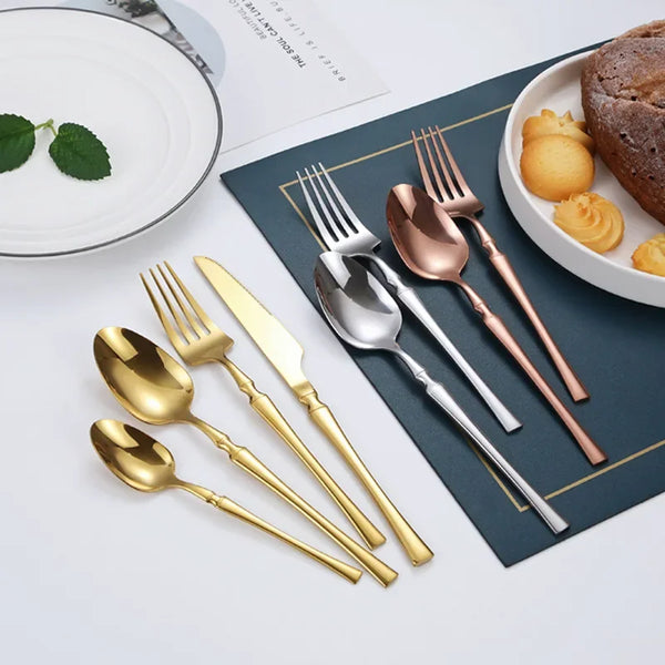 Set aus Edelstahlbesteck (Messer, Gabel, Löffel) auf blauem Servietten mit Gebäck.