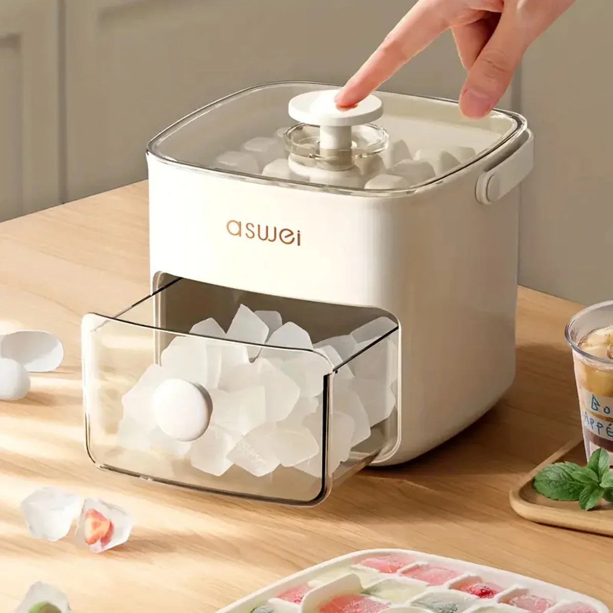A hand is shown placing an ice cube into a white plastic ice cube maker with a clear compartment.