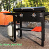 A black silicone BBQ baking mat is shown outdoors on a wooden stand with orange accents.