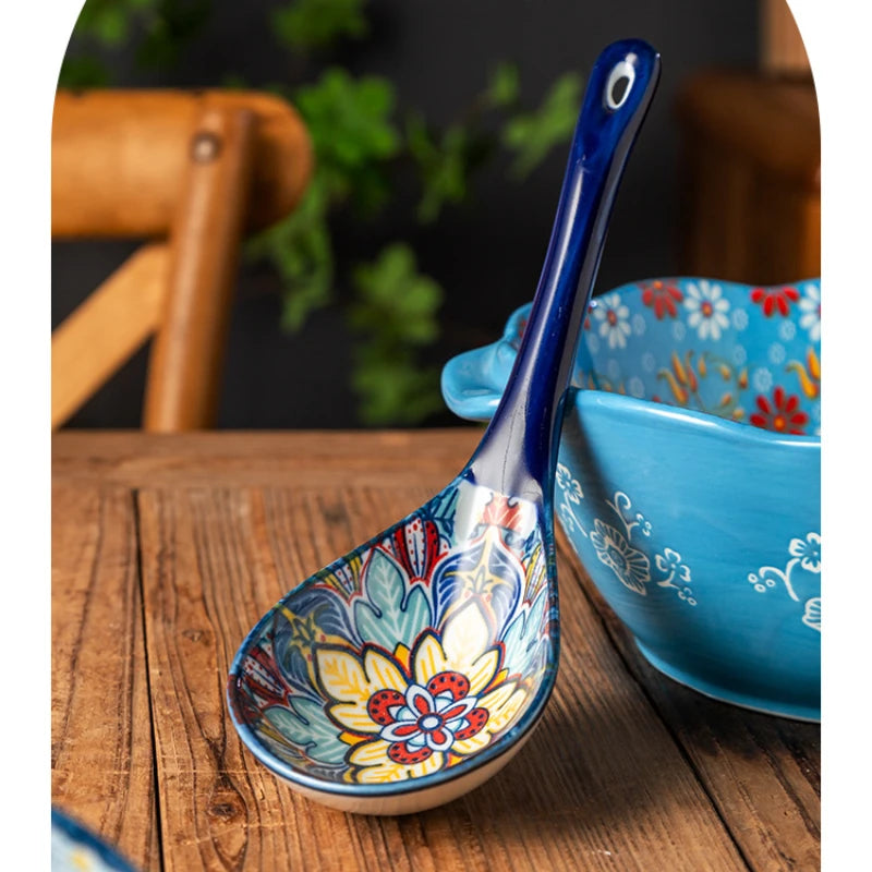 A blue ceramic ladle with floral patterns rests in a matching bowl on a wooden surface.