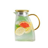 A large glass water jug with a gold-colored handle filled with water and citrus slices.