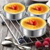 Six stainless steel nonstick baking rings holding bright red strawberries and blueberries on a wire rack