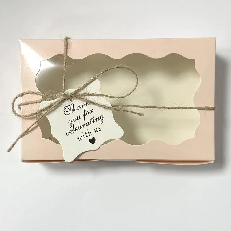 A light pink decorative kraft paper candy box tied with natural twine and a handwritten thank you note.