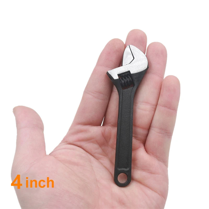A hand holds a small, silver and black compact mini adjustable spanner wrench.