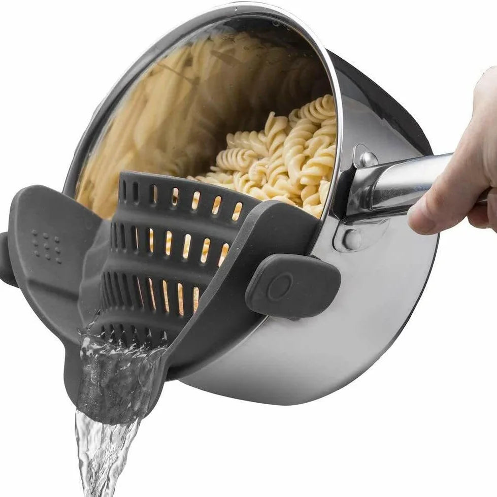 A hand is pouring water through an adjustable silicone clip-on strainer that is used for pasta and vegetables.