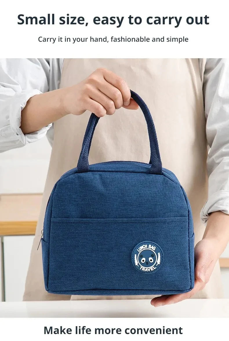 A hand holds a navy blue insulated lunch bag with a circular travel logo against a light background.