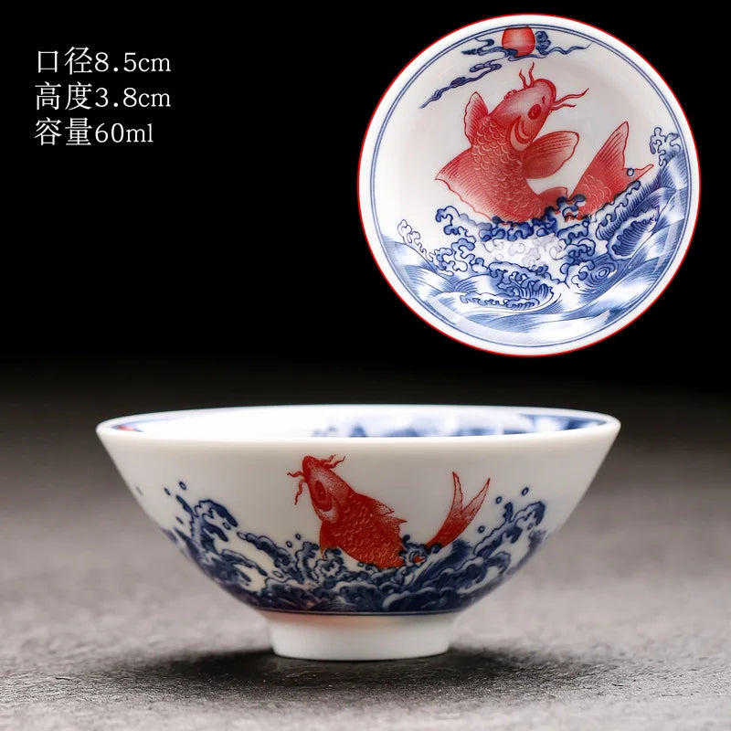 A white porcelain bowl with blue and red designs featuring fish motifs, shown against a dark background.