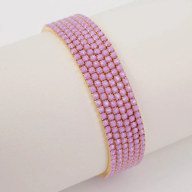 A close-up of a purple acrylic elastic bracelet stacked on a white wrist.
