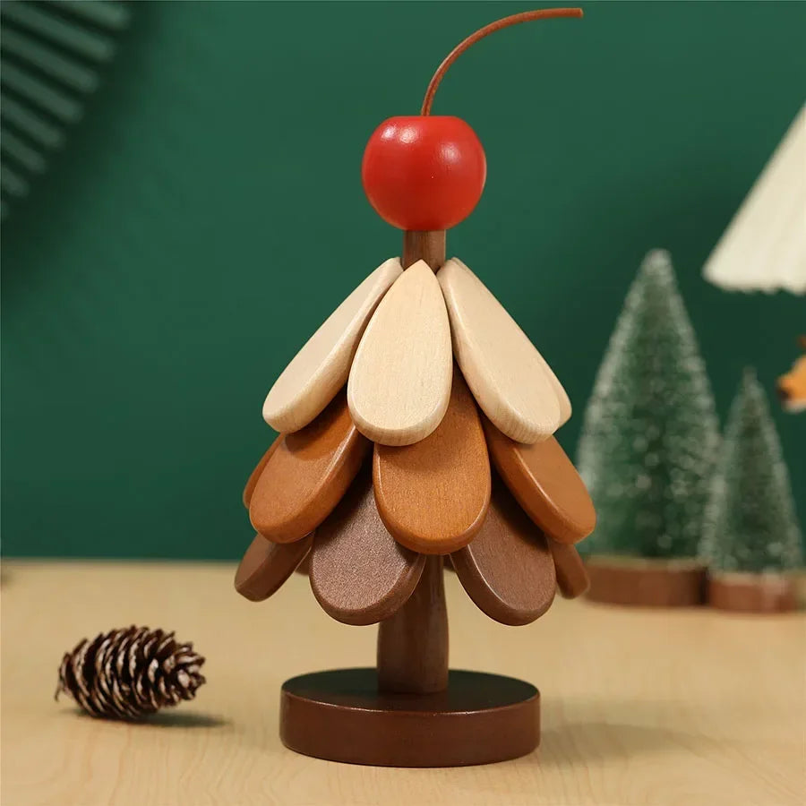 A natural wood foldable trivet shaped like a Christmas tree with layered leaves and a red berry on top.