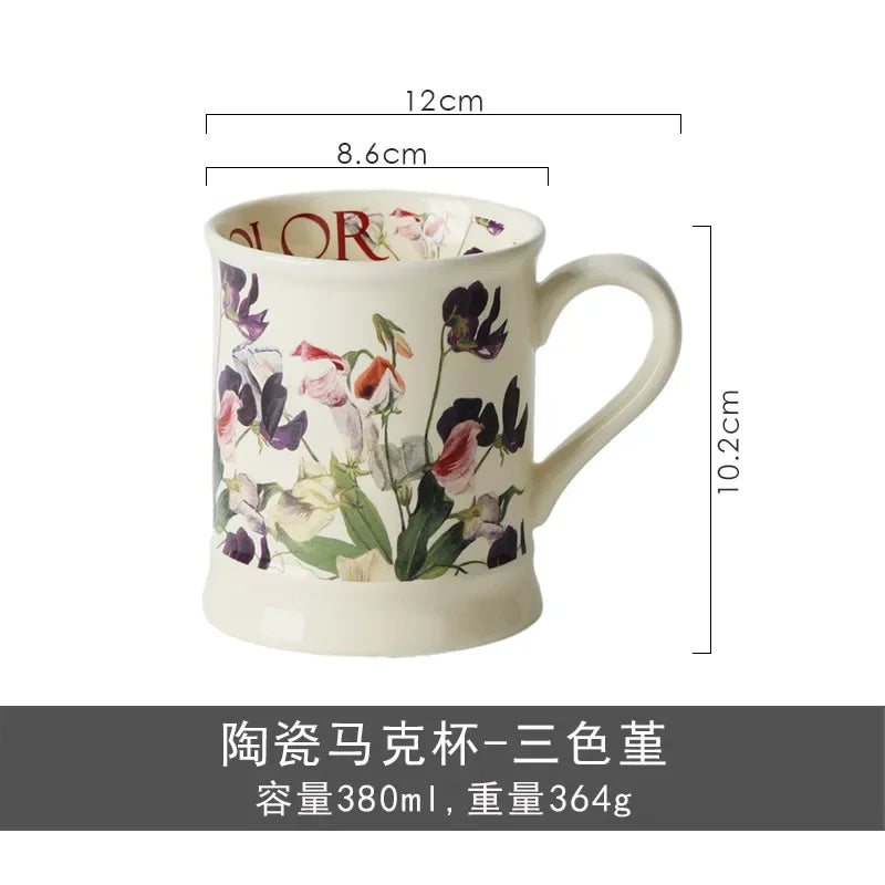 A white ceramic coffee mug featuring a floral design in shades of purple, pink, and green.