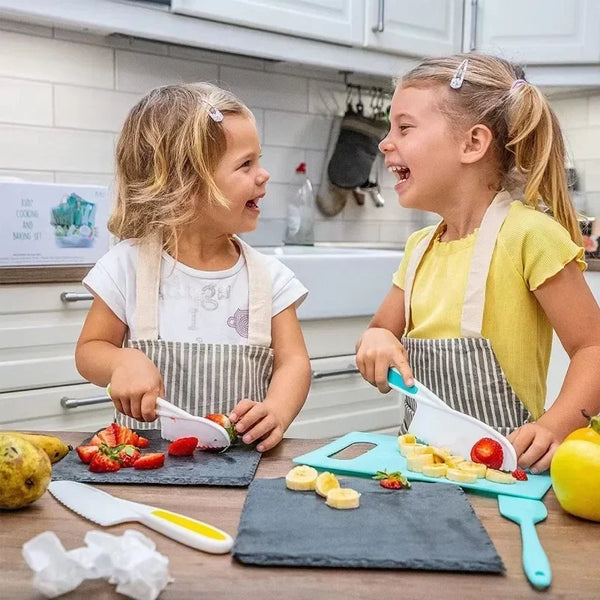 Zwei junge Kinder benutzen ein buntes Obst- und Gemüse-Satz, um Essen in der Küche zuzubereiten.