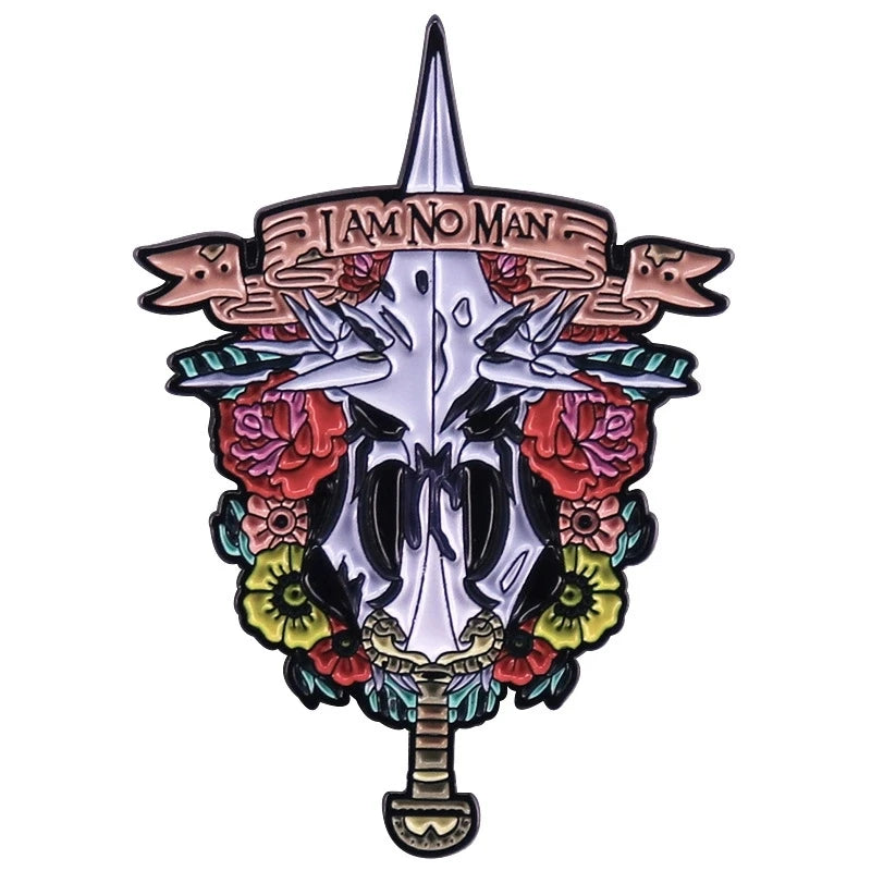 A silver enamel pin featuring a skull design with the text I AM NO MAN and surrounding floral elements.