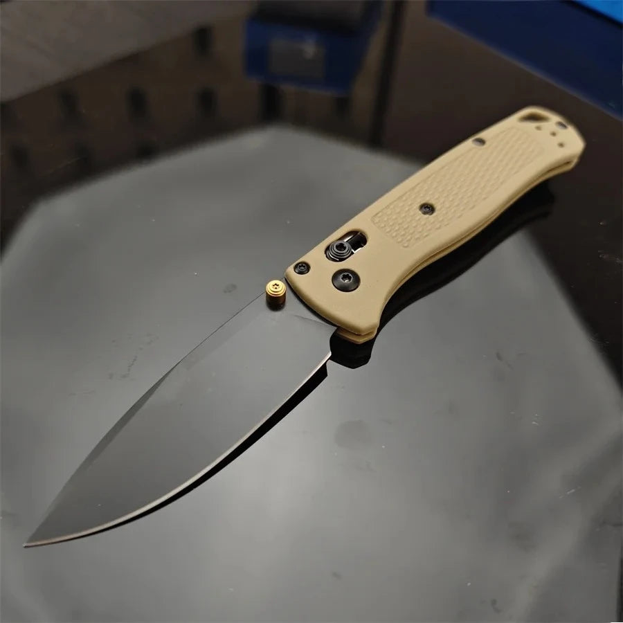 A folding utility knife with a light tan handle and a dark blade is shown resting on a dark surface.