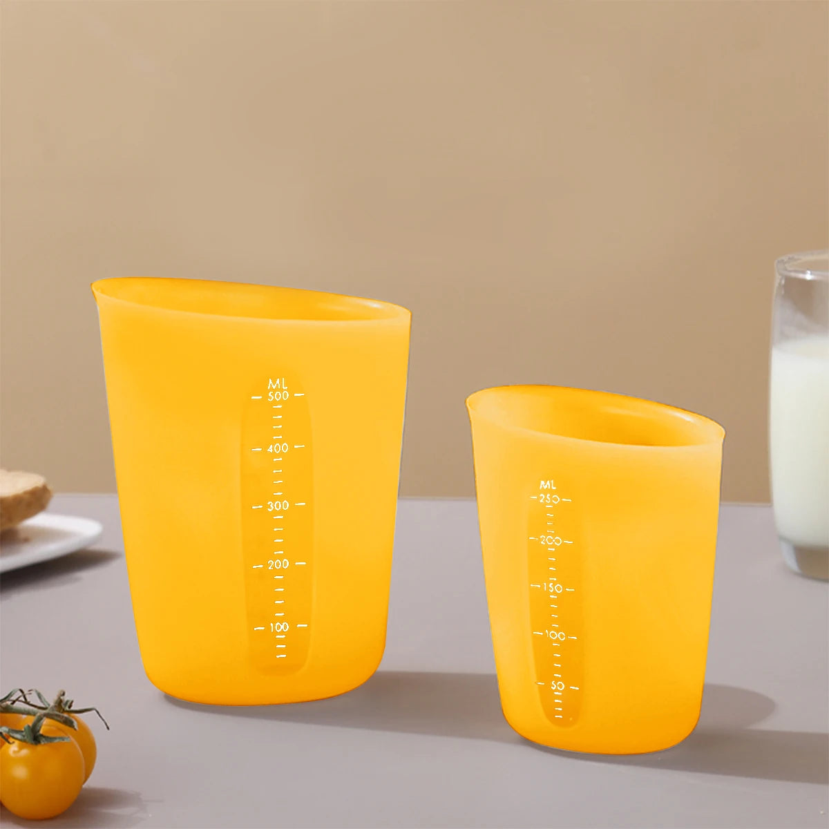 Two bright orange silicone measuring cups with volume markings are displayed on a light surface.