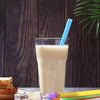 A glass of light-colored beverage with a blue straw is set against a dark wooden background.