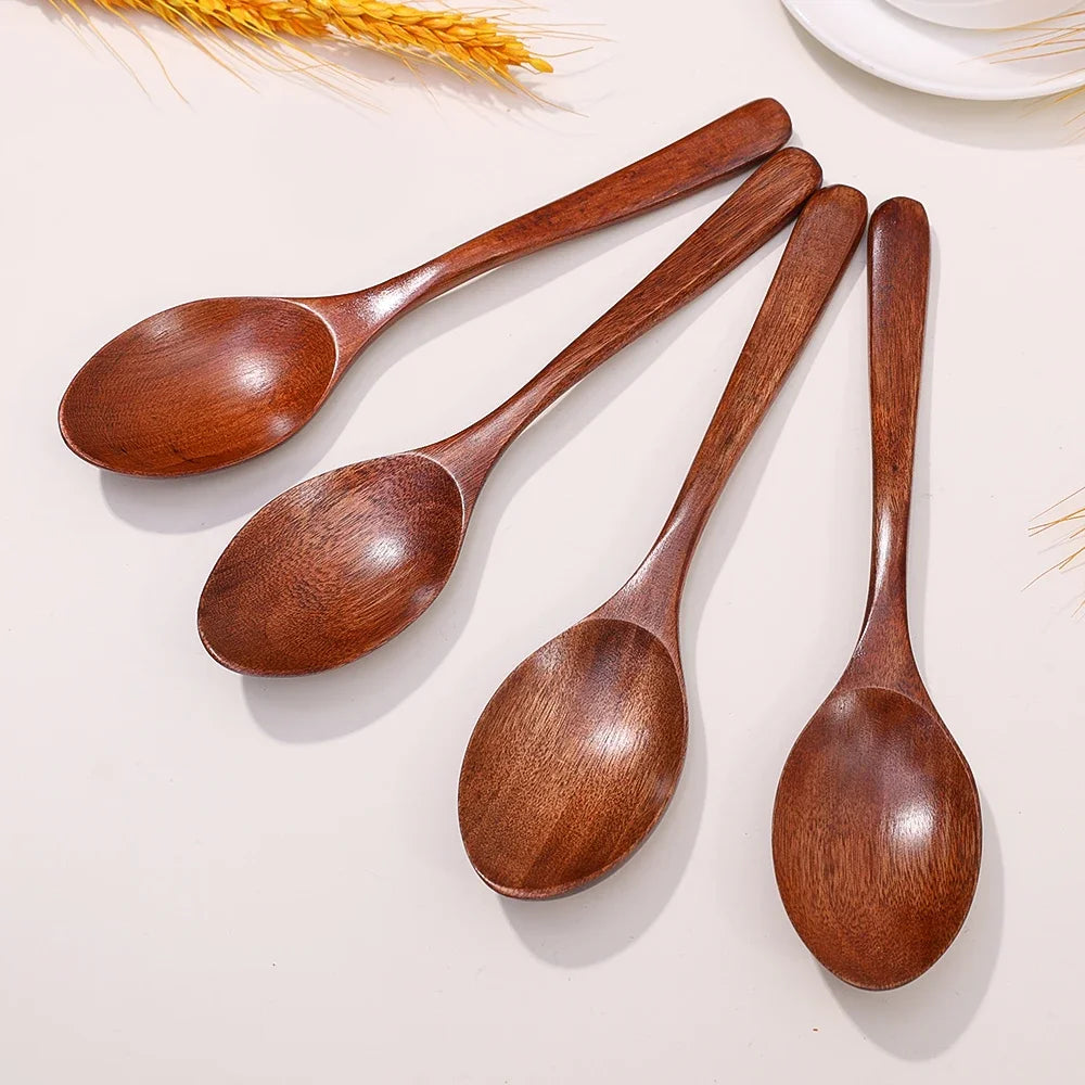 A set of four natural wooden serving spoons arranged on a light background.