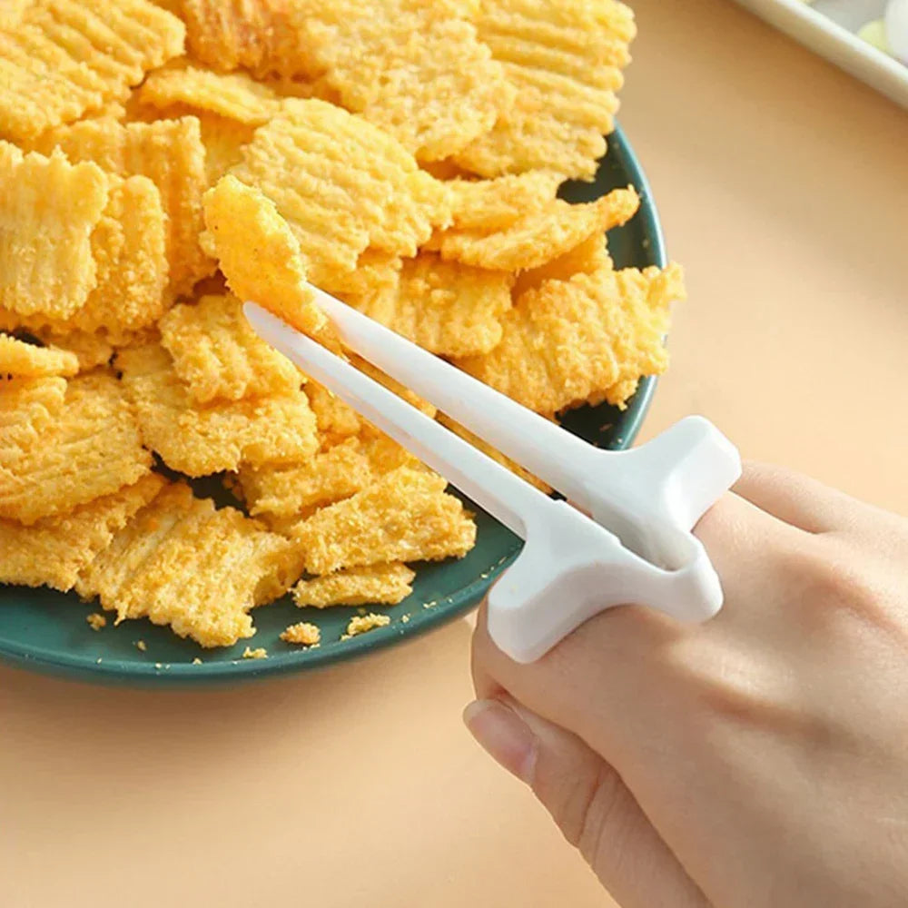 A hand holds white precision finger chopsticks poised over a pile of golden potato chips.