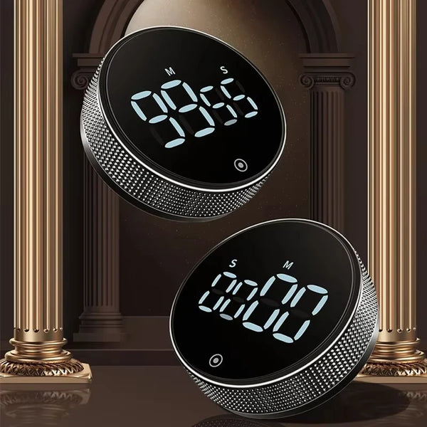 Nahaufnahme eines schwarzen magnetischen Küchentimers mit digitaler Anzeige 09:55 vor dunklem Hintergrund.