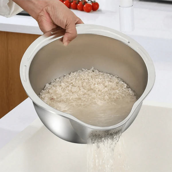 Eine Hand gießt Wasser in eine Edelstahl-Reiswaschschüssel, die Reis wäscht.