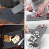 A set of dark gray marble texture anti-slip cutting boards and a knife being used to cut meat.