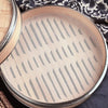 A round silicone steamer liner with a perforated mesh bottom is shown on a dark surface.