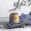 A glass of coffee served with a straw on a wire rack, resting on a blue cloth.