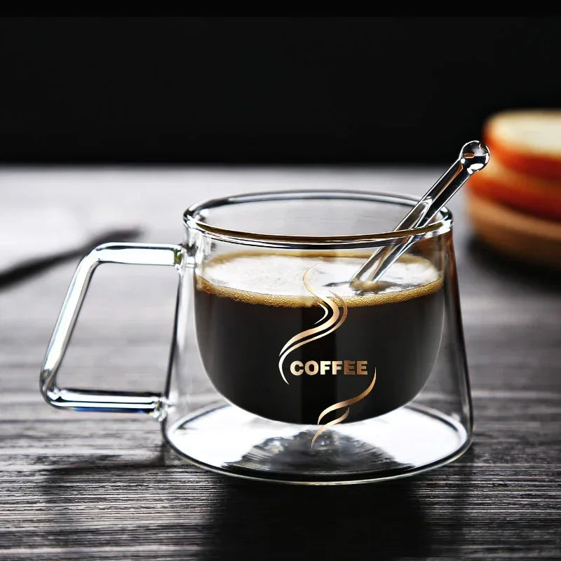A clear double-walled heat-resistant espresso cup filled with dark coffee, featuring a swirling logo.