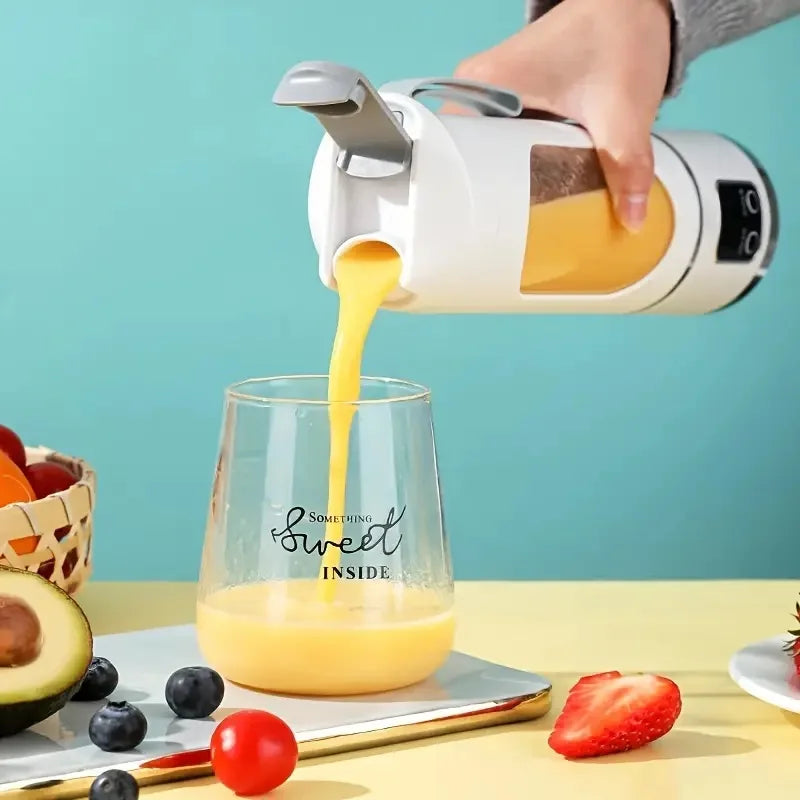 A hand is pouring orange juice from a white portable handheld juicer blender into a glass.
