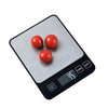A precision digital kitchen scale with three red spheres placed on the weighing platform.
