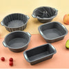 A set of gray silicone baking molds, including muffin cups and cake pans, displayed on a light background with fruit.