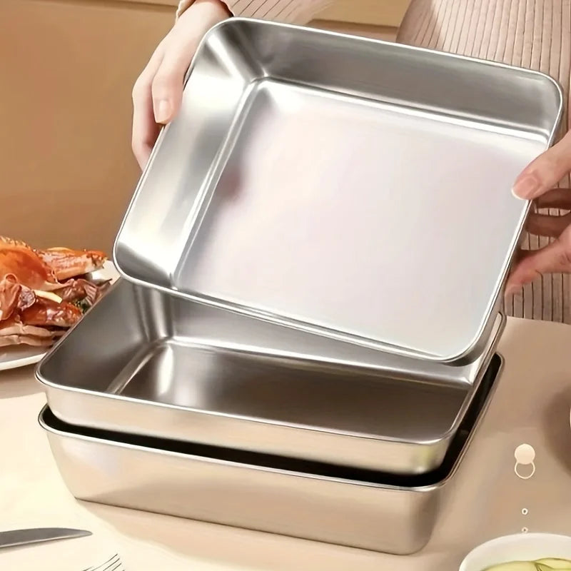 A hand is holding an open stack of stainless steel food storage containers, showing the nested design.