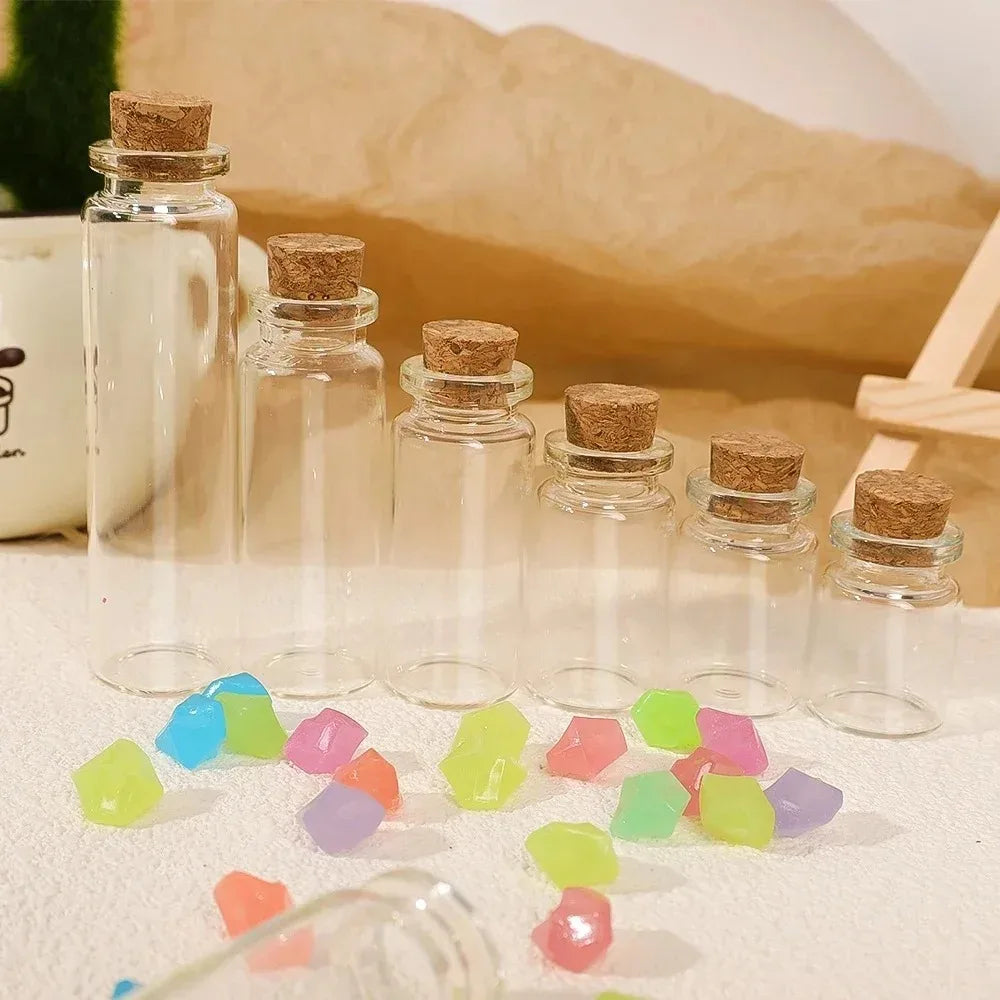 A set of decorative glass message and wishing bottles filled with colorful glass gems on a light surface.