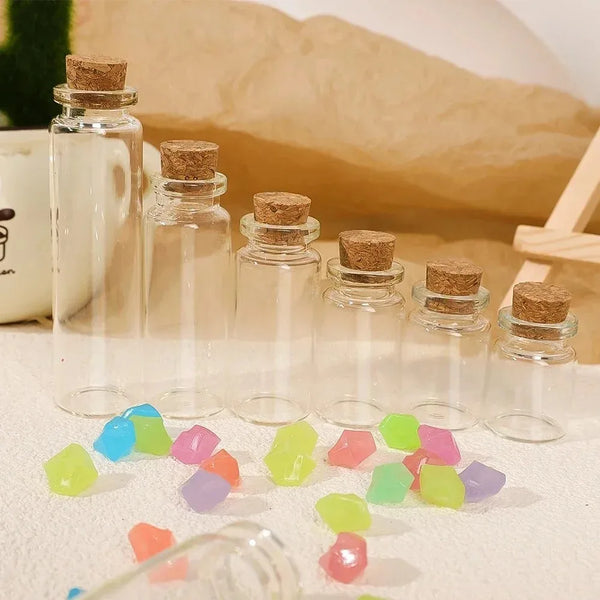 A set of decorative glass message and wishing bottles filled with colorful glass gems on a light surface.