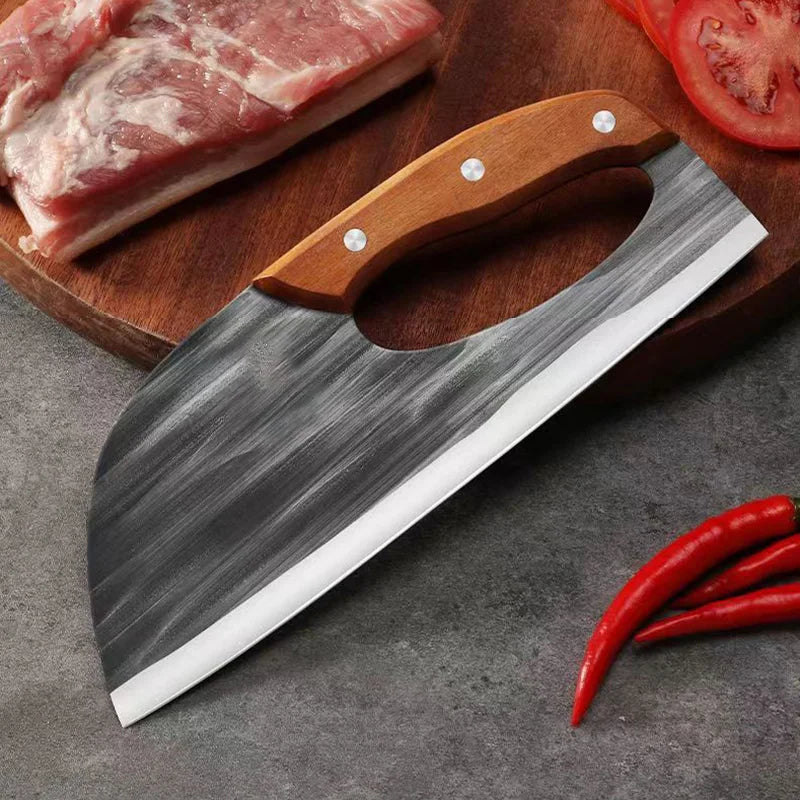 A hand forged boning knife with a wooden handle and black blade is shown next to raw meat and a tomato slice.