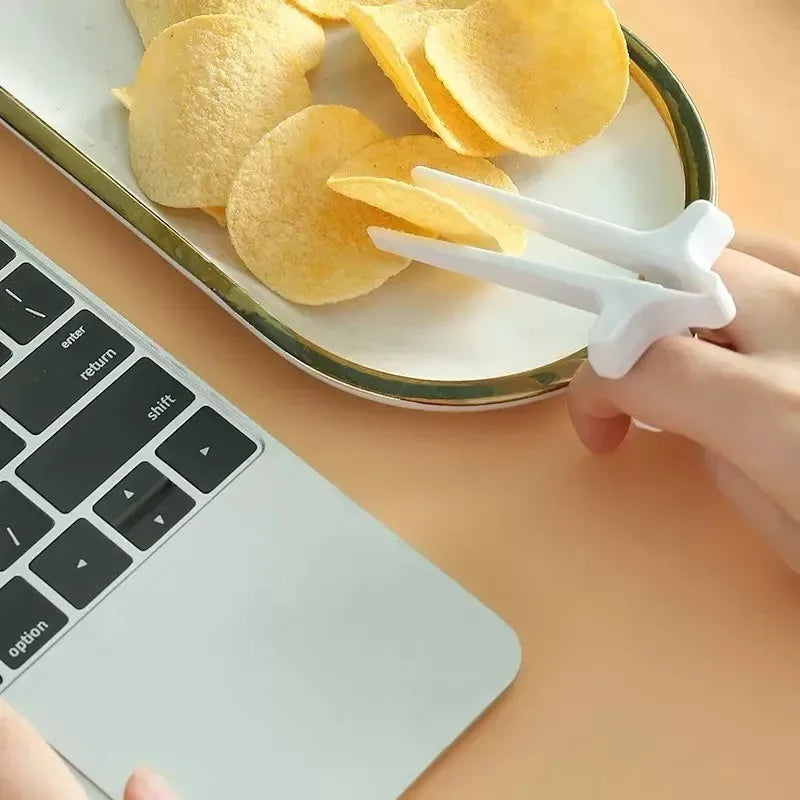 White finger guard chopsticks holding tortilla chips on a laptop keyboard