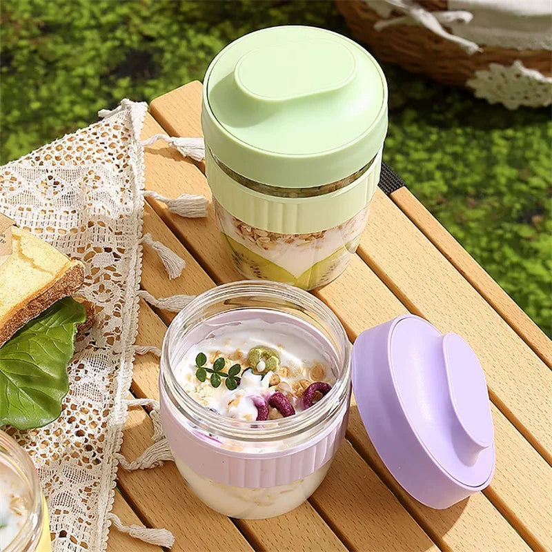 A clear glass jar of yogurt or smoothie with a light green lid and a purple clamp-top container on a wooden surface.