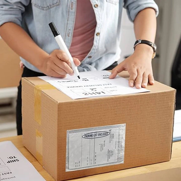 A person is sealing a cardboard box with a handwritten label and a packing list inside.