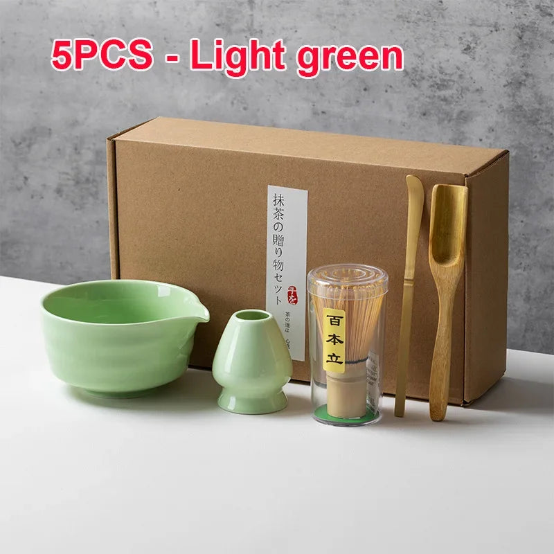 Juego de cinco piezas de té matcha verde claro, incluyendo cuencos y utensilios de bambú, en una caja de cartón.