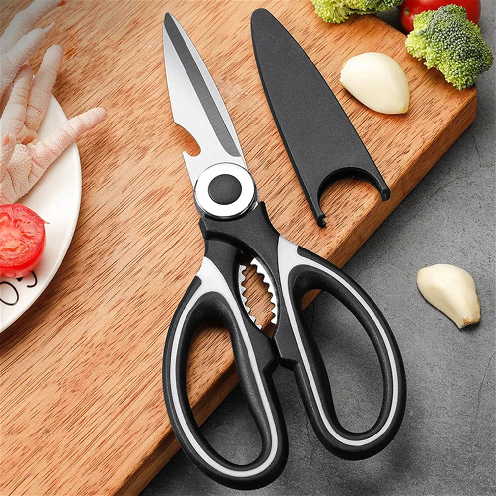 A pair of professional stainless steel kitchen cutting scissors resting on a wooden board with fresh vegetables.