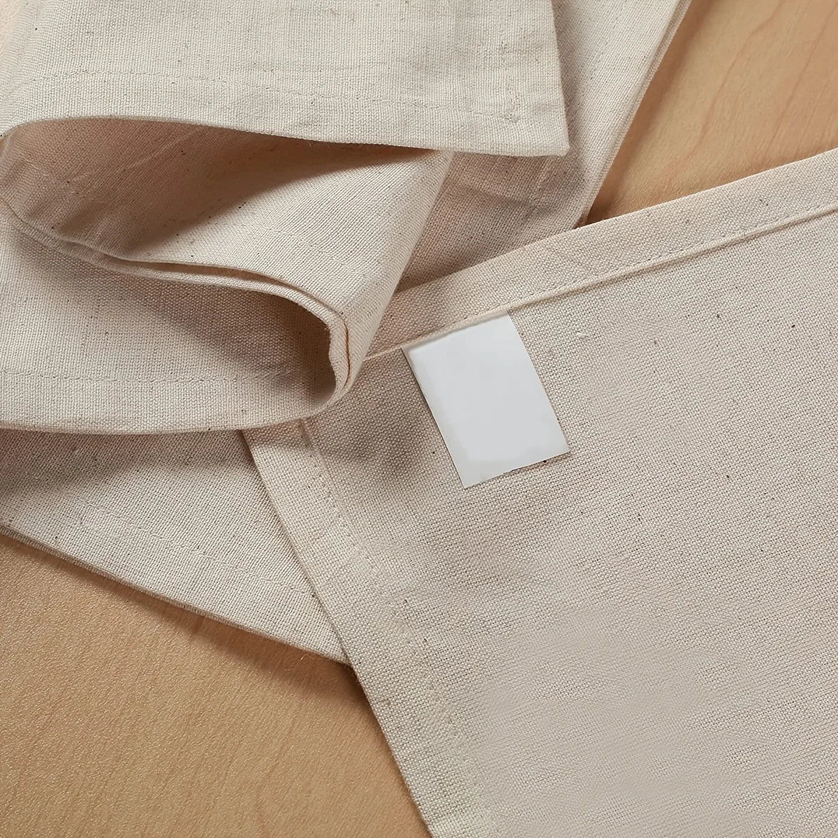 A stack of natural linen table napkins with a white decorative tag placed on one of the fabric pieces.