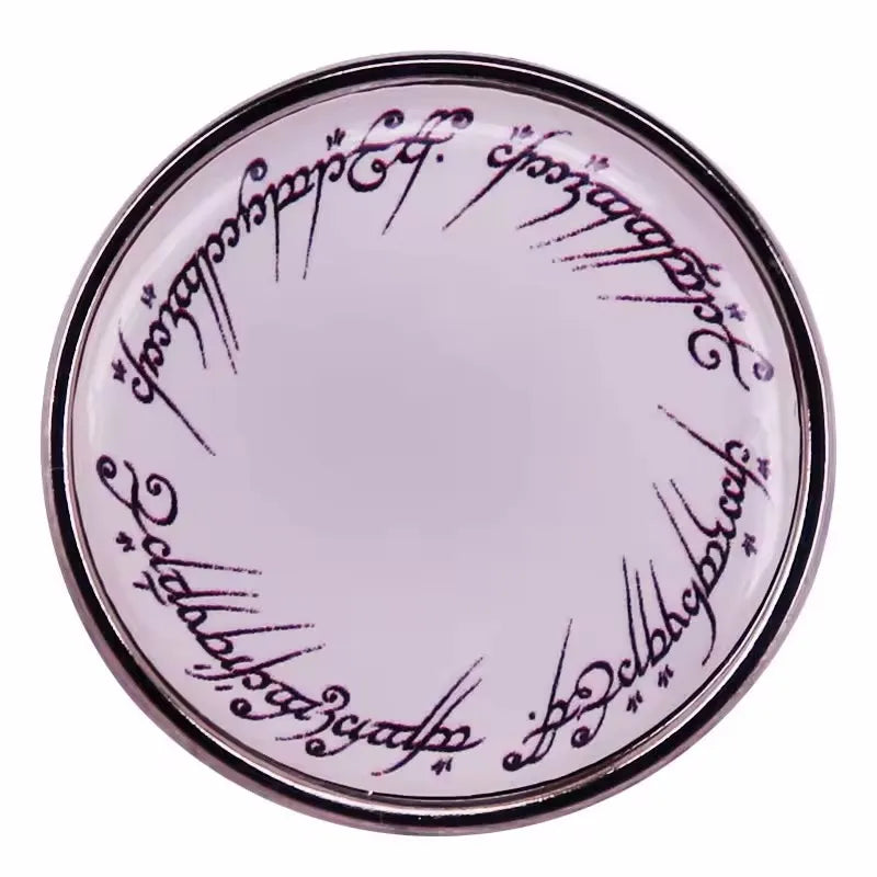 A round enamel pin featuring ornate script on a light pink background.