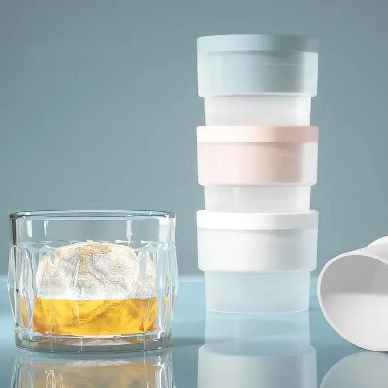A stack of clear glass ice molds with various colored plastic molds for cocktails on a reflective surface.