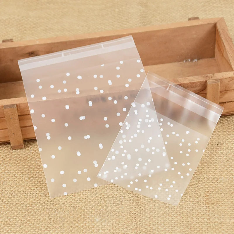 Clear plastic candy cookie bags with white dots are displayed in a wooden box.